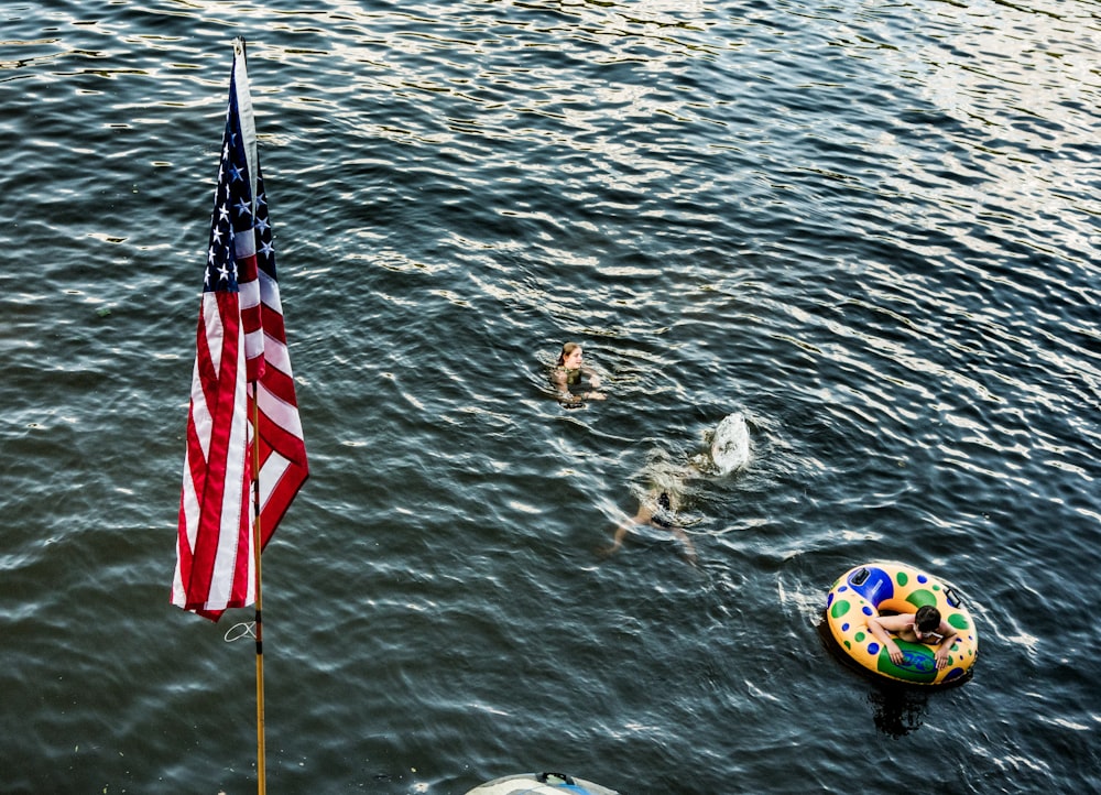 tre persone che nuotano in uno specchio d'acqua vicino alla bandiera degli Stati Uniti