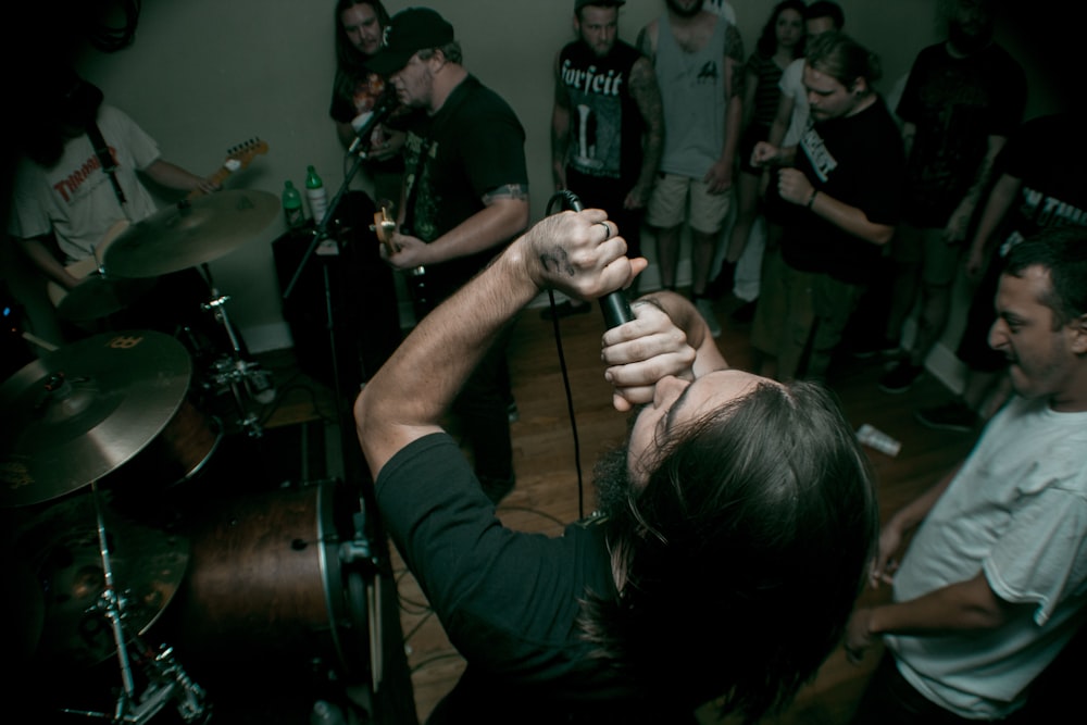 man holding black corded microphone near man wearing white crew-neck t-shirt