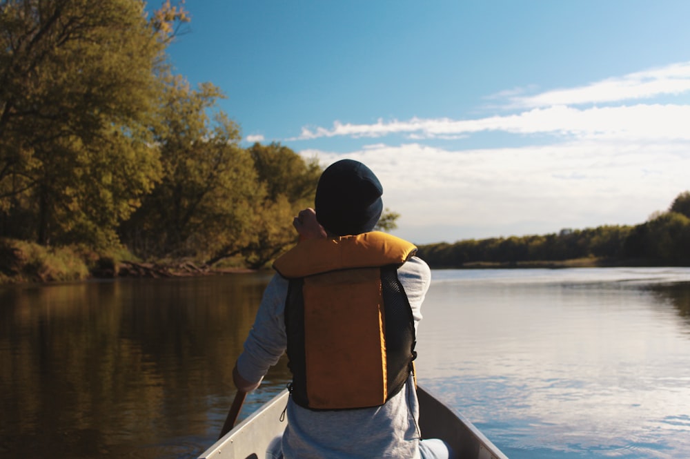 person wearing flotation vest rowing boat