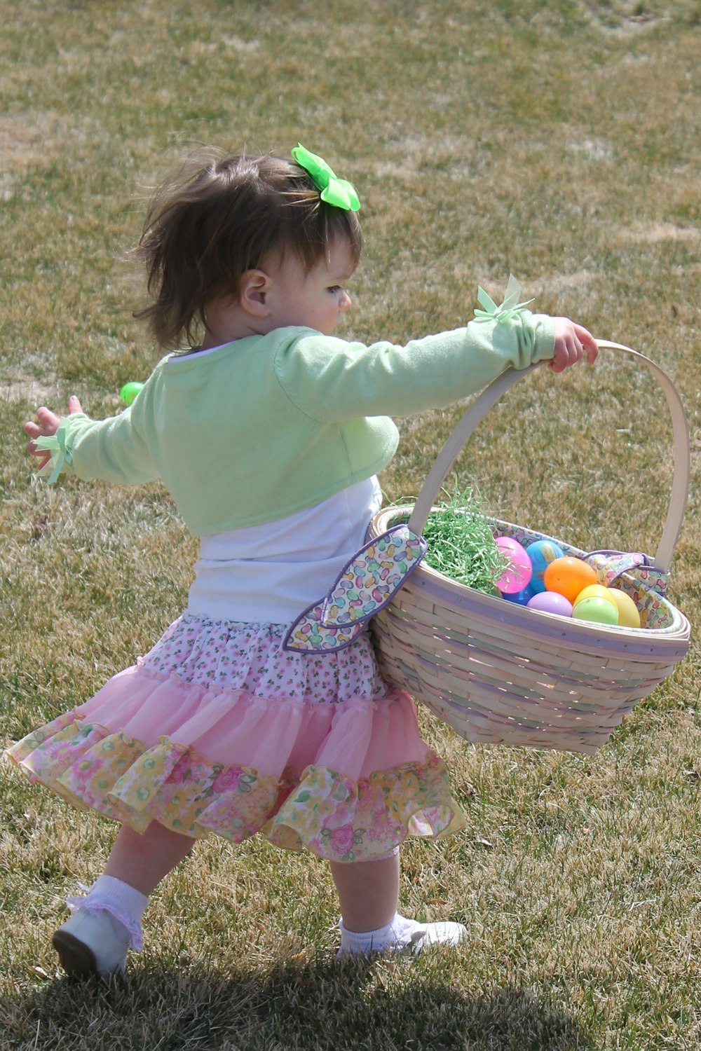 A girl carrying plastic eggs in an Easter basket.