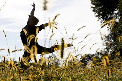 Dancers smiling and moving rhythmically on a grassy field surrounded by trees