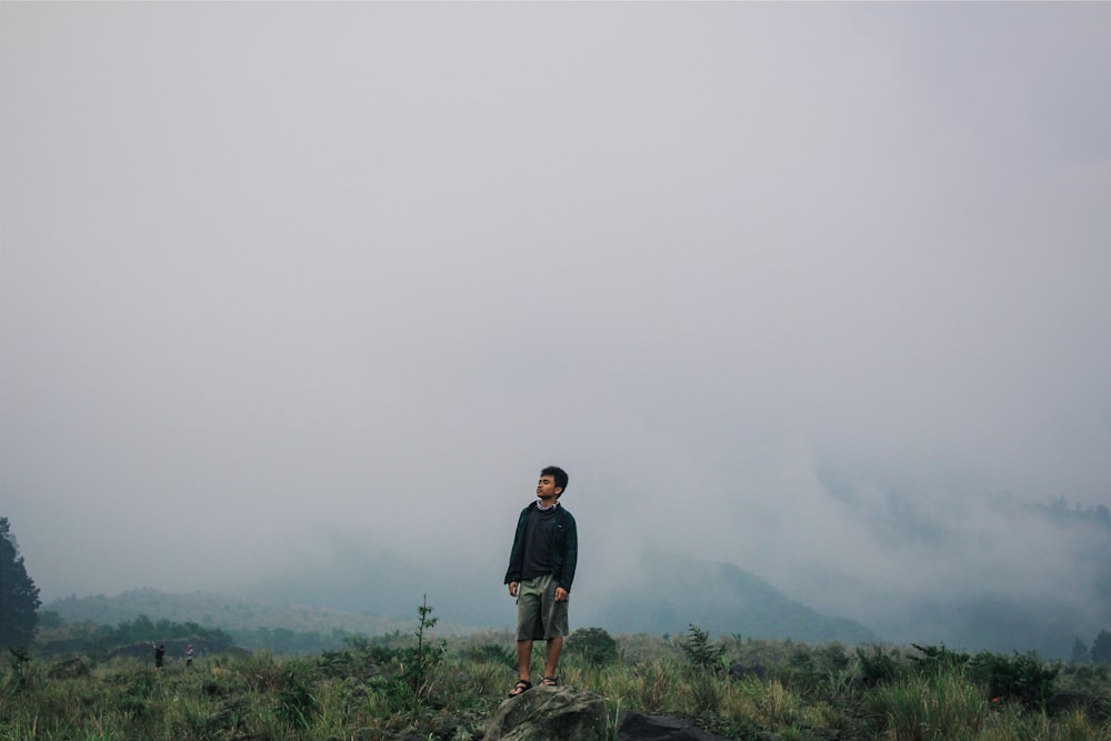 man standing on gray stone under cloudy sky