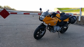 A bright yellow motorcycle on a charcoal-colored road with safety cones.