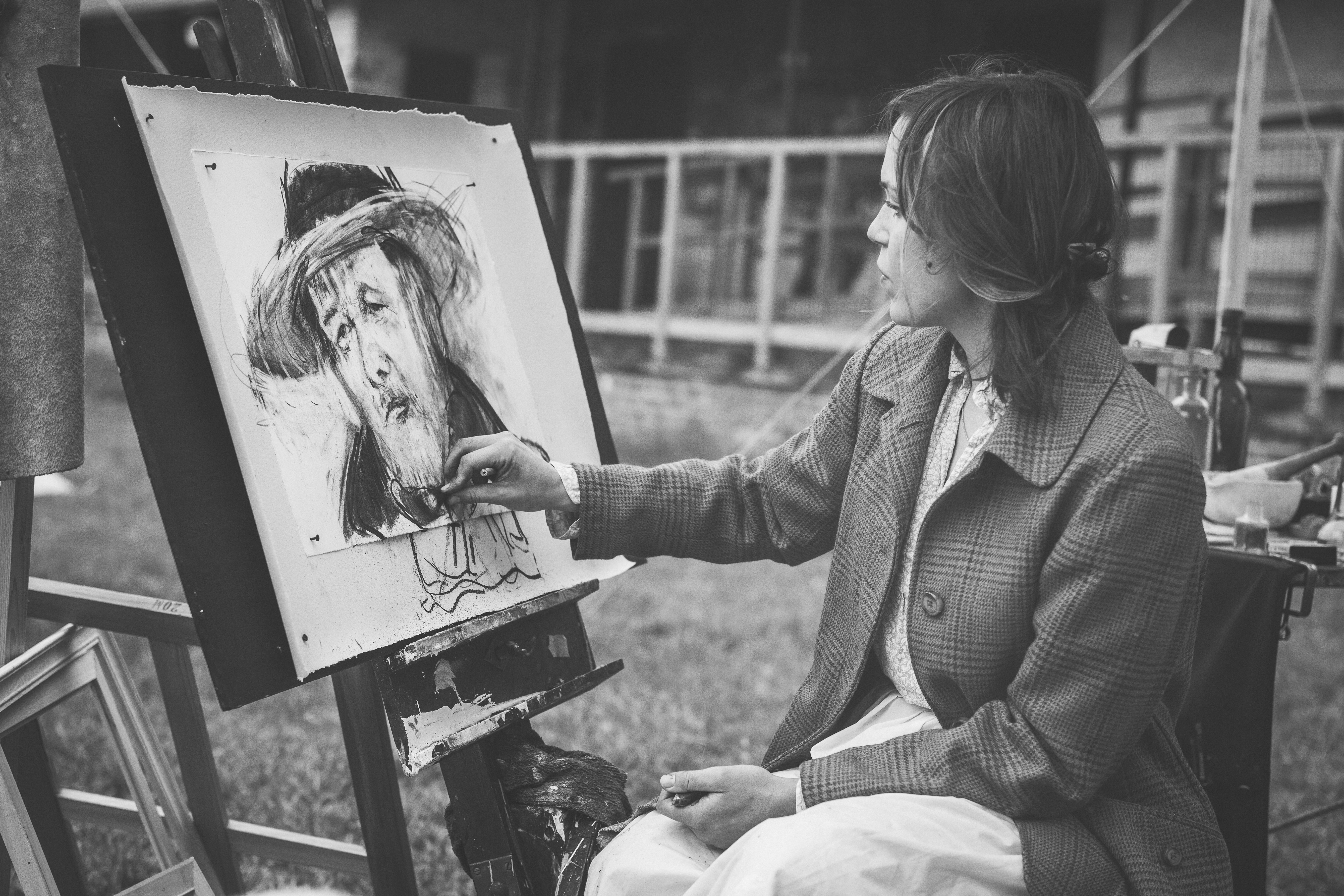 grayscale photography of woman sitting while painting