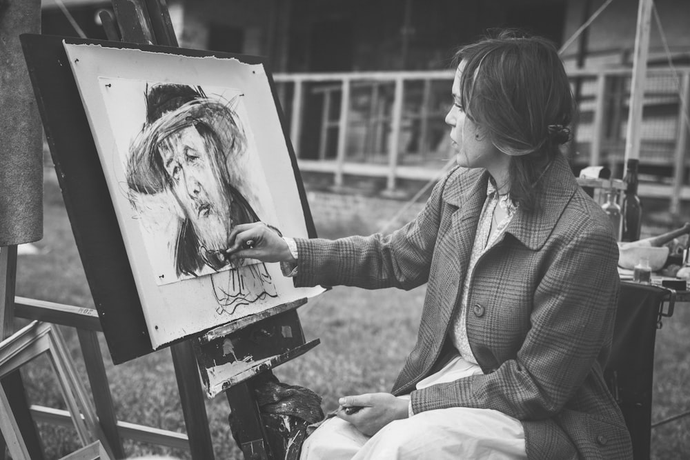 그림을 그리는 동안 앉아있는 여자의 회색조 사진