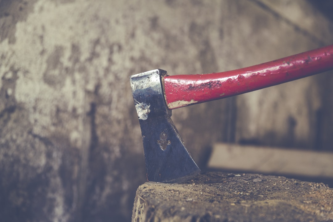 red and black axe on wood slab,