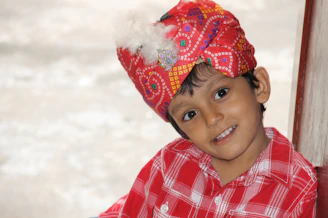 A joyful Indonesian child wearing a colorful kurta, holding a printable activity sheet from daskar.id