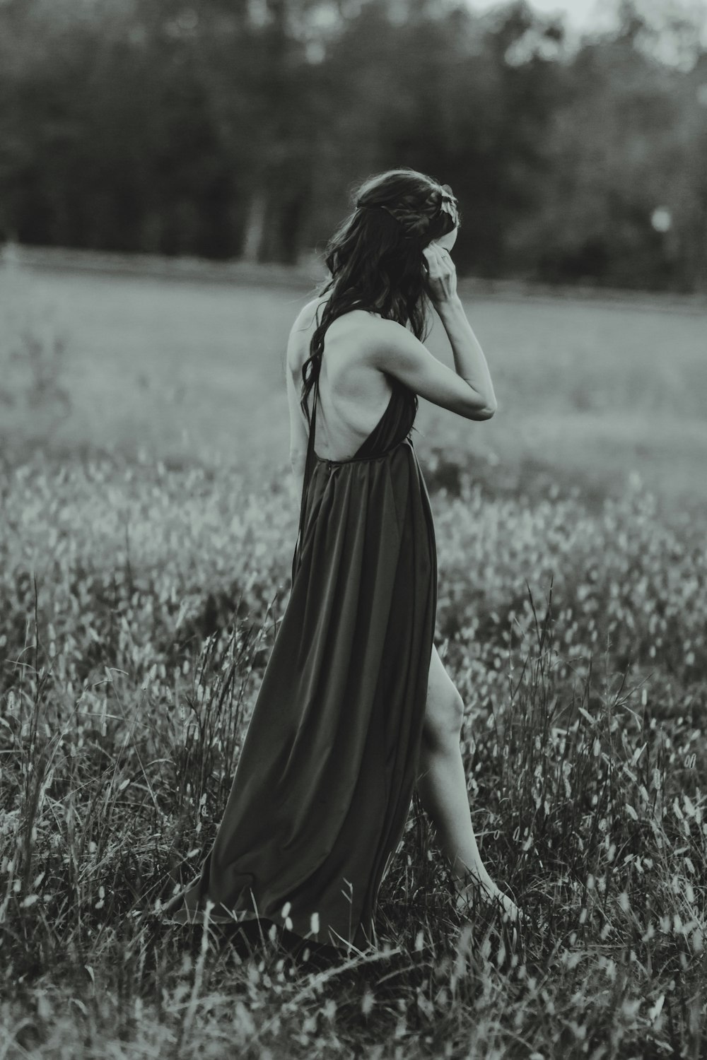 fotografia in scala di grigi di donna che indossa un vestito sul campo d'erba mentre è in piedi