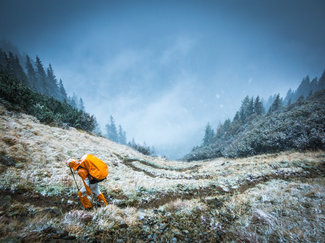 A mountaineer in bright orange clothes on a grassy slope in winter