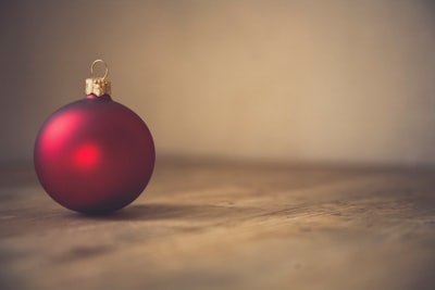closeup photo of red ball ornament on surface holly zoom background
