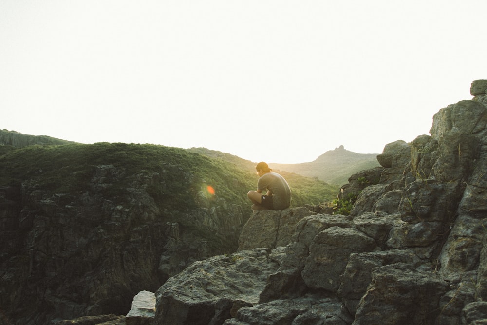 man sitting near cliff during sunrise
