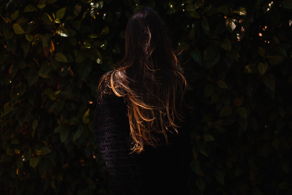 woman standing in front of green leaves