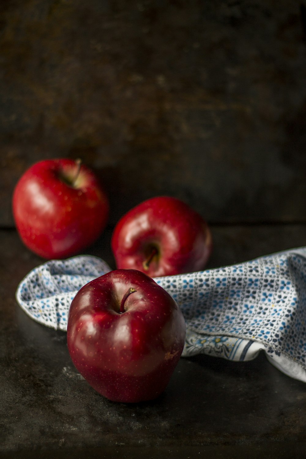 trois pommes rouges sur une surface brune