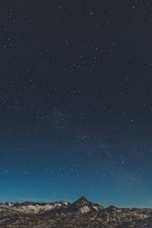 Illustration of a mountain range with stars twinkling above, blending science icons subtly into the night sky.