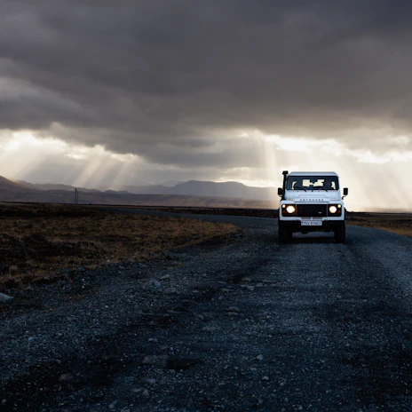 Jeep winding along a rugged mountain trail under a cloudy sky.
