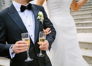 man holding two champagne flutes near woman