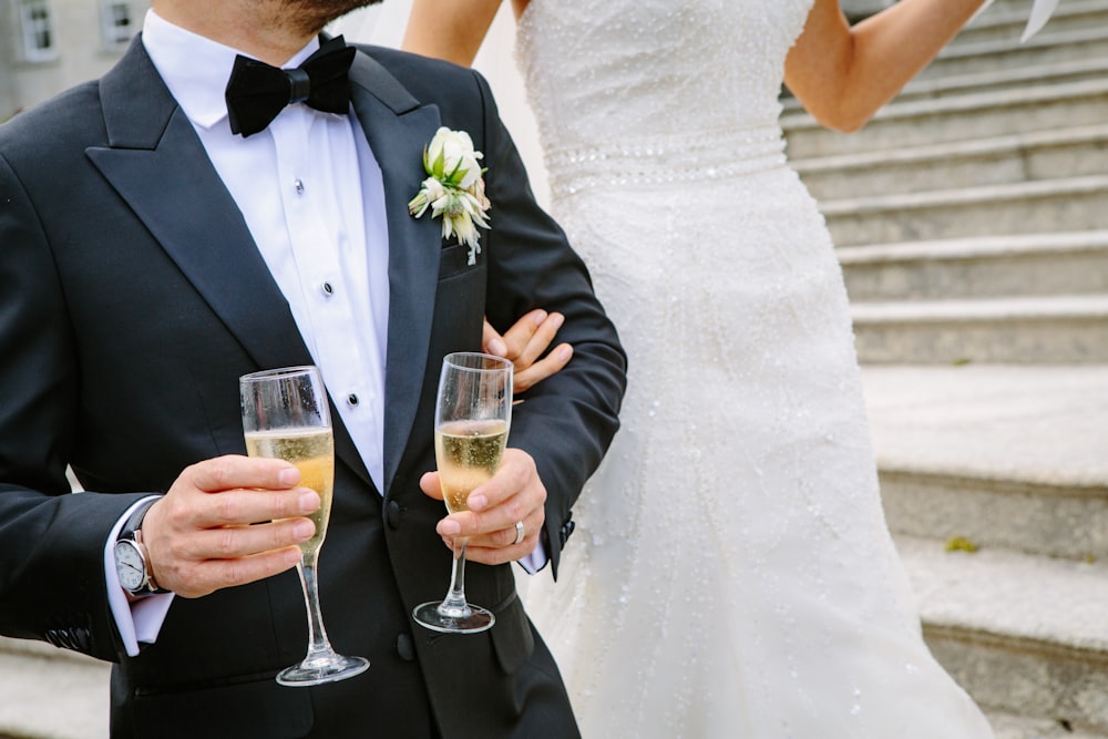 man holding two champagne flutes near woman