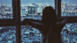 A silhouette of the author gazing out a window with a city skyline at twilight.