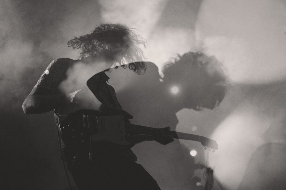 Uma foto em preto e branco de um homem tocando guitarra elétrica em dupla exposição