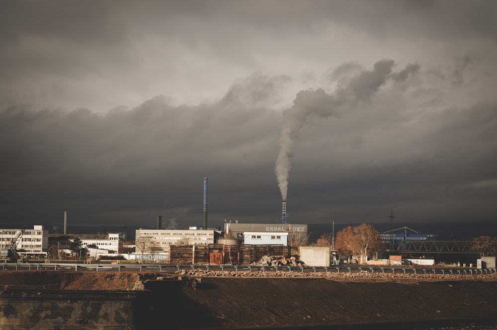 edificio gris con humo bajo nubes blancas