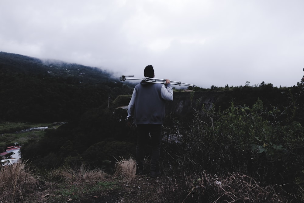 man holding gray metal stand surrounded grass