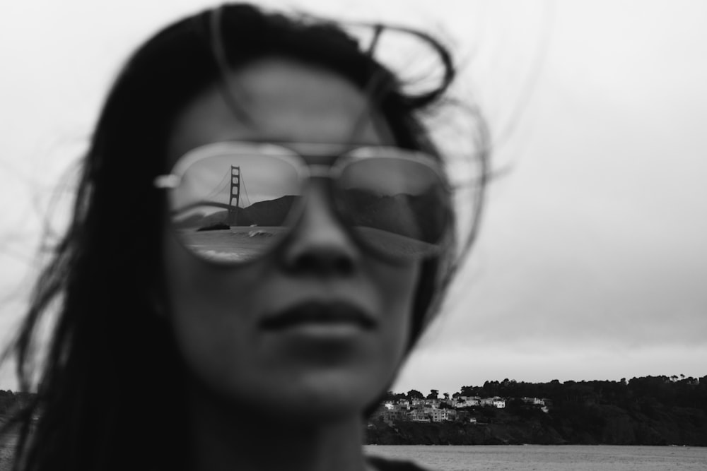 Golden Gate Bridge reflecting on woman's sunglasses in grayscale photo