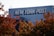 A building with the logo 'NEW YORK POST' prominently displayed on its exterior. In the foreground, autumn-colored leaves are visible under a clear sky.