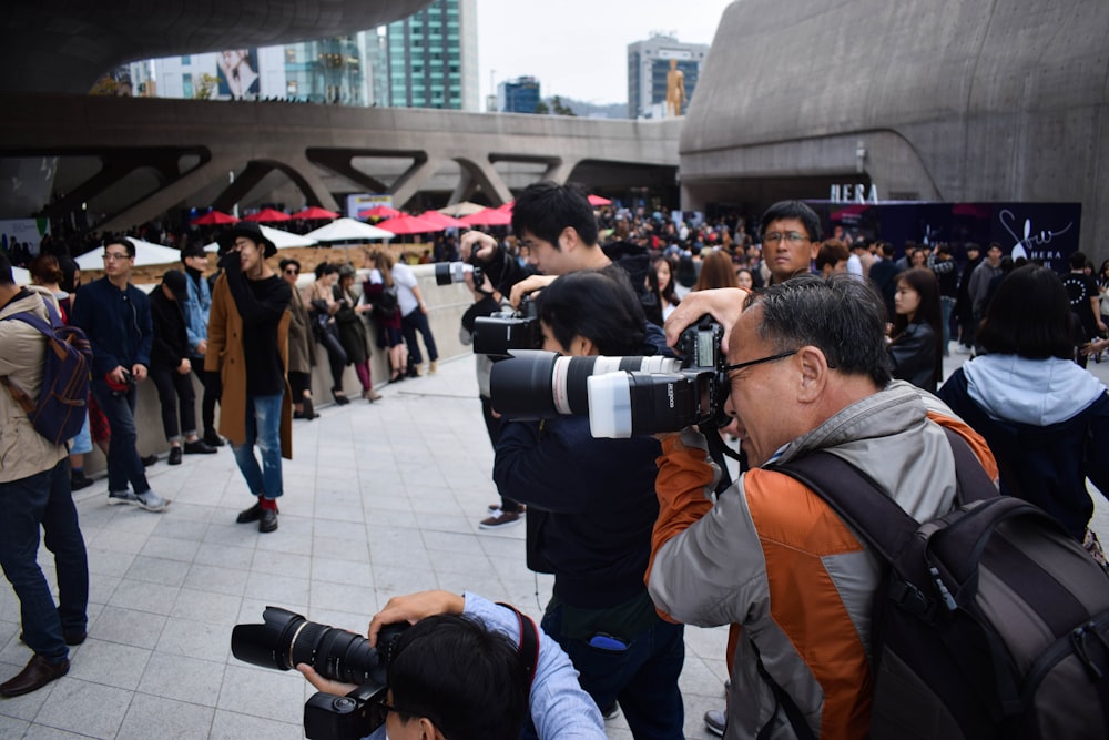 Gruppe von Fotografen, die tagsüber DSLR-Kameras in der Veranstaltung halten