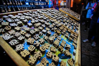 An array of wooden blocks with engraved Chinese characters, likely used for printing or stamping. The scene is vibrant, with an array of blocks neatly arranged on trays, surrounded by dim lighting. There's a focus on the intricate detail of the characters, each one carefully crafted.