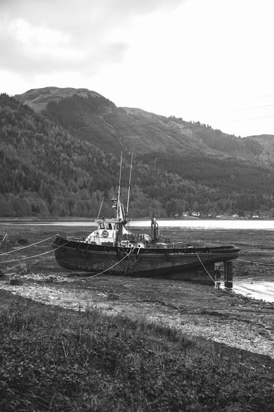 grayscale photo of boat on sea near mountain in Kyle of Lochalsh United Kingdom