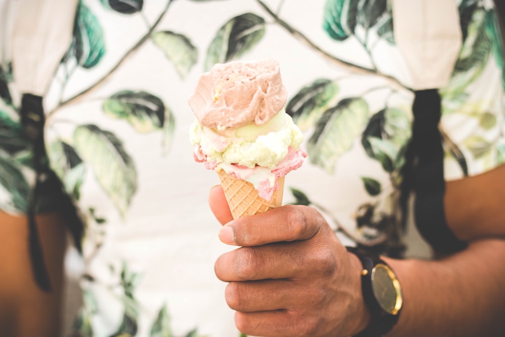 person holding ice cream cone with three flavors of ice cream