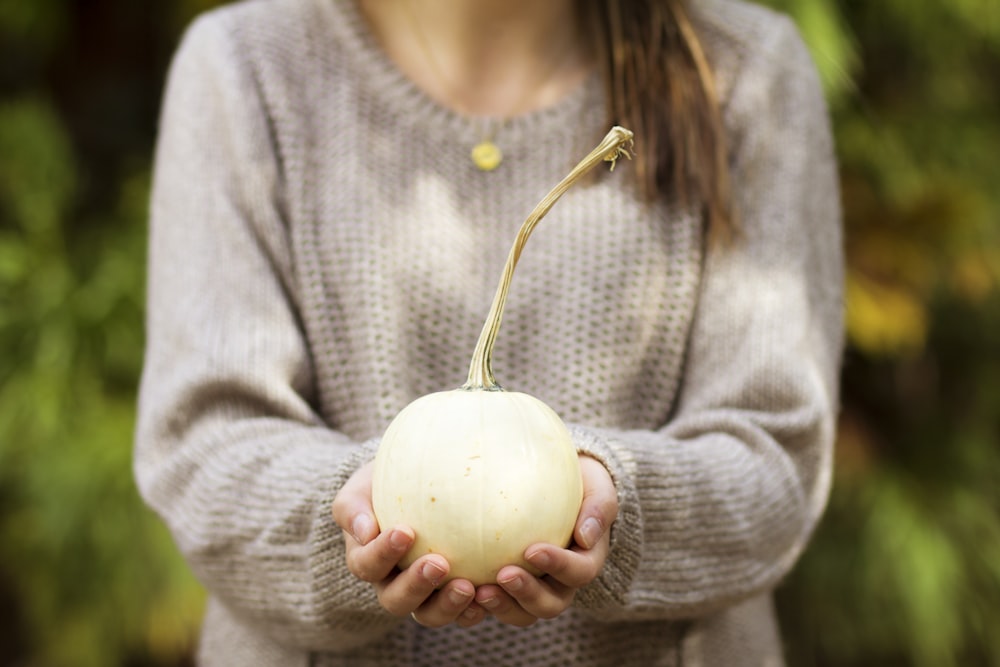 Mujer sosteniendo fruta redonda blanca al aire libre