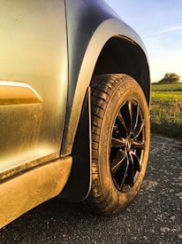 Close-up of a sparkling clean car exterior reflecting sunlight on a rural road.