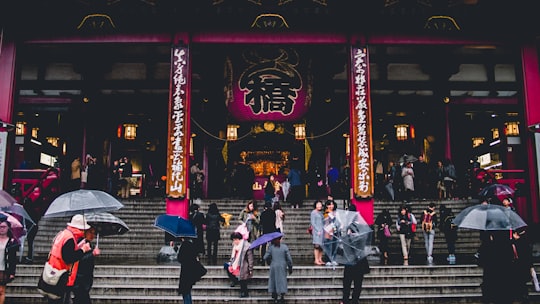 people walking on concrete stairs in front of temple in Sensō-ji Japan