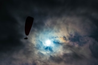 A cautious paraglider looking at stormy skies, symbolizing risk awareness.