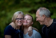 photo of two man and one woman standing near tree