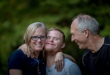 photo of two man and one woman standing near tree