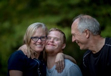 photo of two man and one woman standing near tree