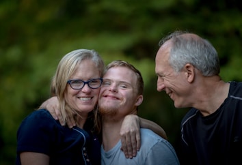 photo of two man and one woman standing near tree