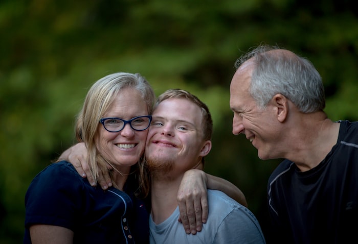 Padres mayores abrazando a su hijo, todos sonriendo