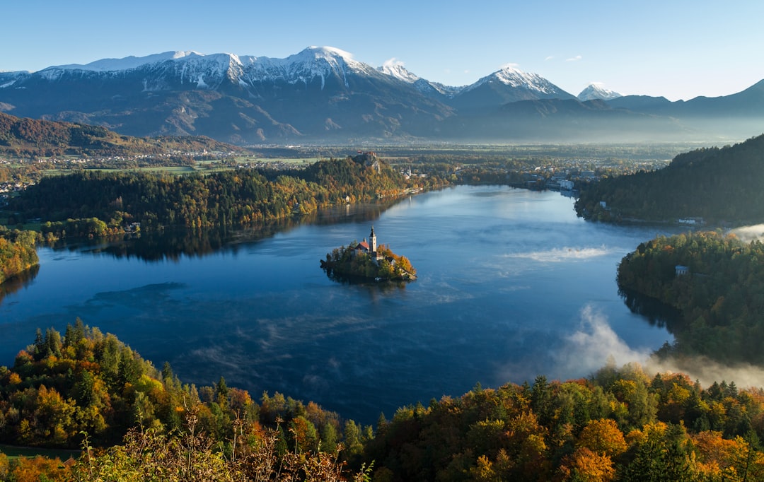 island surrounded by water and mountains at daytime, Church on a lake in the mountains