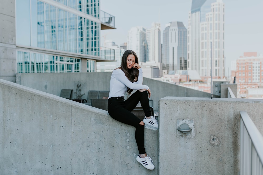 woman sitting on concrete building