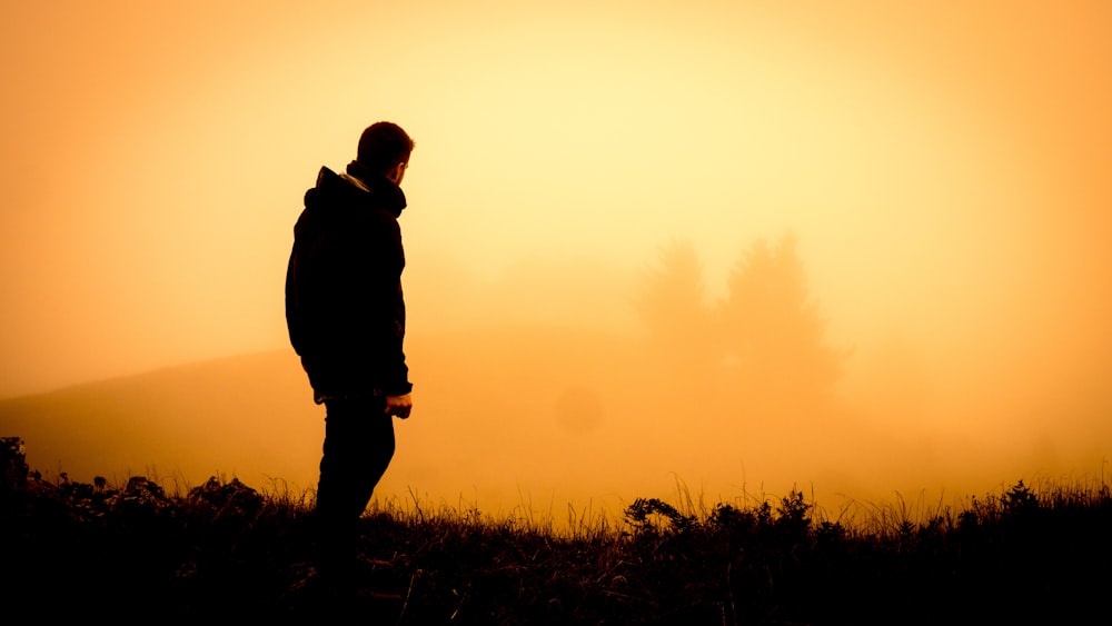 Silhouette eines Mannes, der auf offenem Feld steht