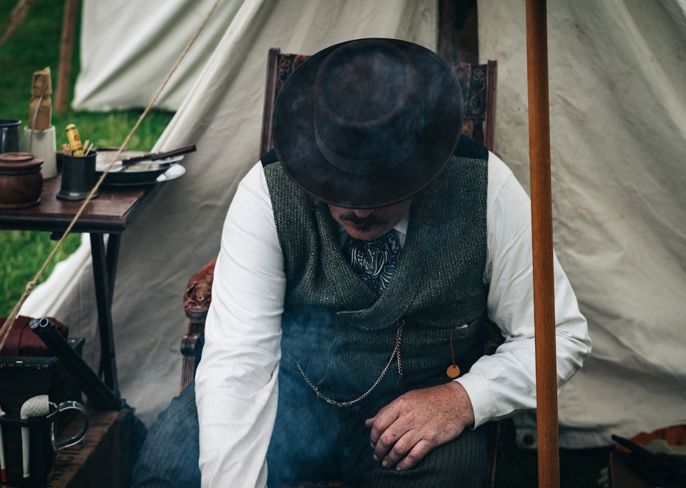 man sitting on chair beside tent