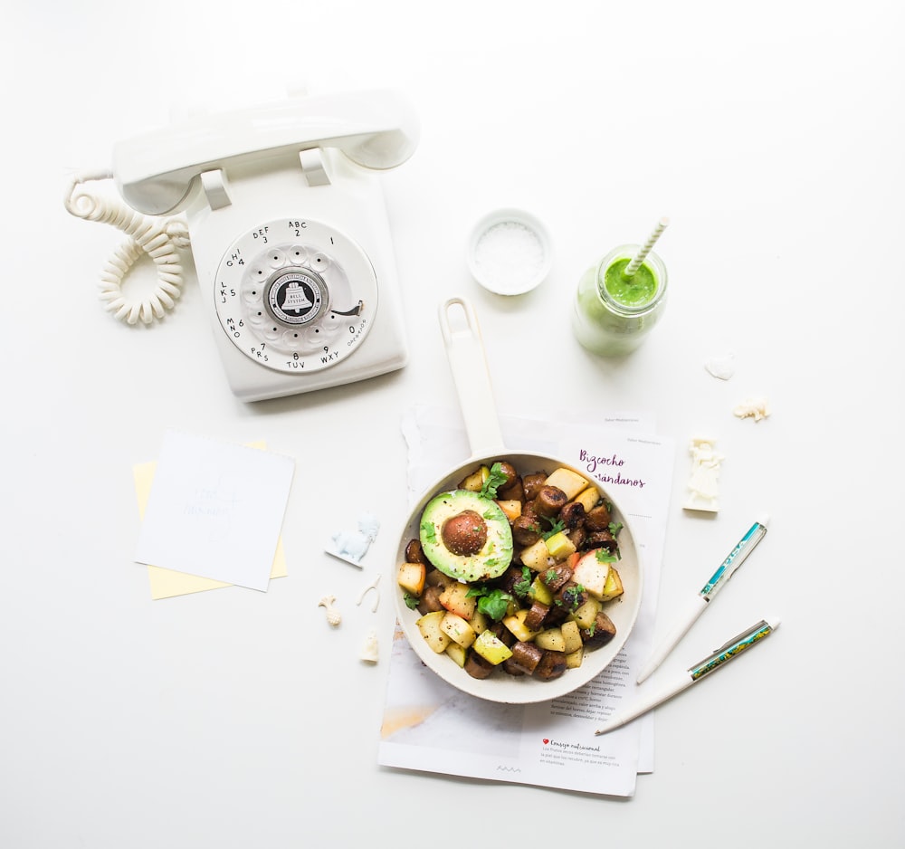 sliced avocado fruit inside bowl near rotary phone beside jar