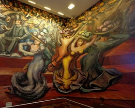 A vibrant mural depicting stylized figures in motion. People are dressed in early 20th-century attire, characterized by top hats and elaborate gowns. The composition features dynamic lines and exaggerated forms, suggesting movement and energy.