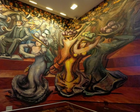 A vibrant mural depicting stylized figures in motion. People are dressed in early 20th-century attire, characterized by top hats and elaborate gowns. The composition features dynamic lines and exaggerated forms, suggesting movement and energy.