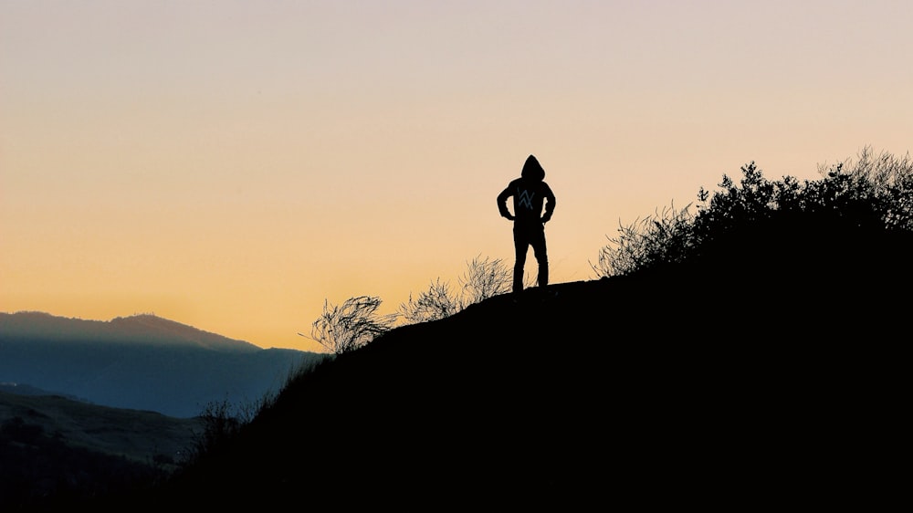 Silhouette einer Person auf dem Gipfel des Hügels während der goldenen Stunde