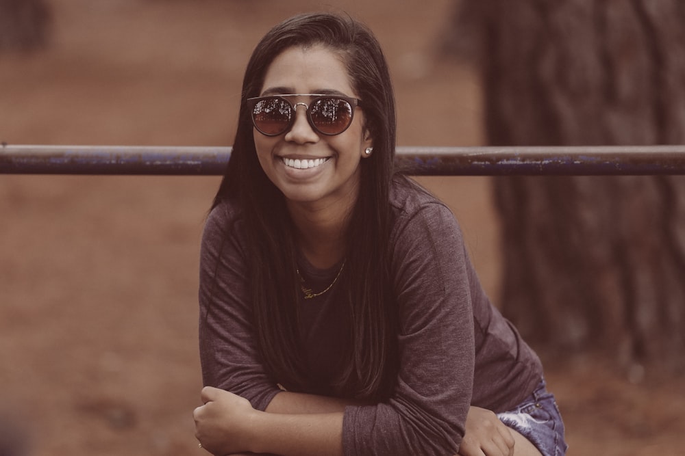 selective focus photography of woman wearing sunglasses and brown long-sleeved shirt near tree