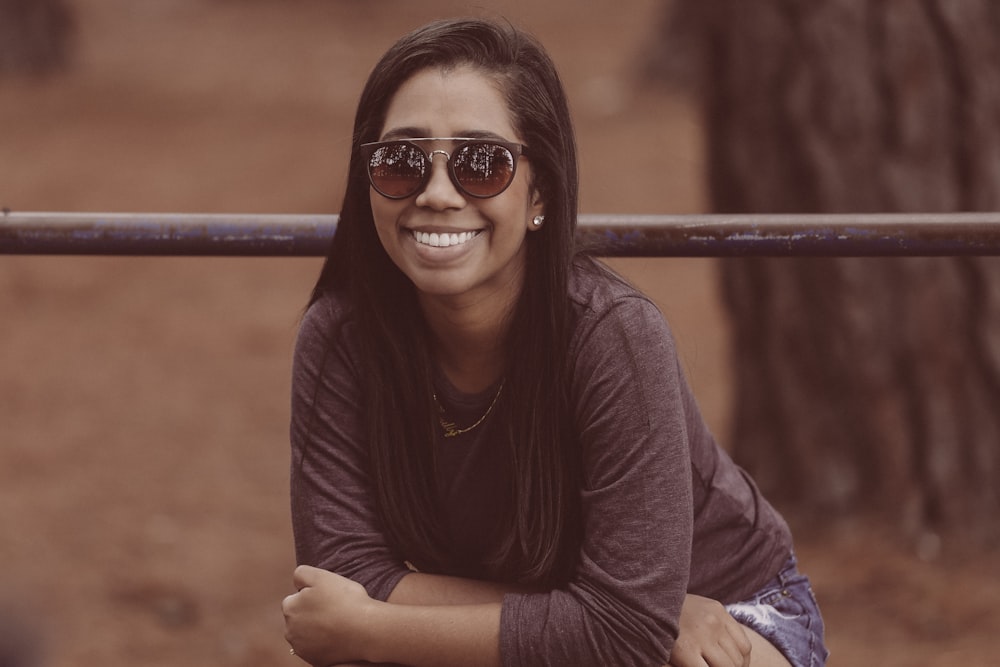 Fotografía de enfoque selectivo de mujer con gafas de sol y camisa marrón de manga larga cerca de un árbol